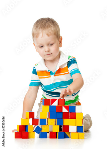 Photo: Child boy playing toy blocks isolated on white Child boy playing toy blocks isolated on white