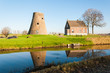 Capless windmill along a ditch in a rural landscape