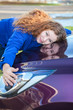 Young female driver hugging hood of new car