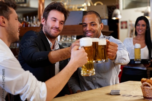 Photo: Friends clinking with beer mugs in pub Friends clinking with beer mugs in pub