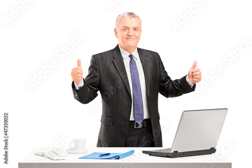 Photo: Happy mature businessman standing and giving thumbs up Happy mature businessman standing and giving thumbs up
