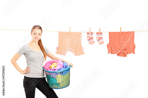 Photo: Smiling woman holding a laundry basket and a laundry line with c Smiling woman holding a laundry basket and a laundry line with c
