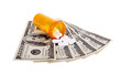 Medication pills in pills bottle with money isolated on white