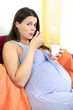 Happy pregnant woman eating yogurt at home
