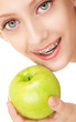 Cute girl in braces with green apple on white background