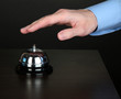 Hand ringing in service bell on wooden table on black