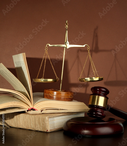 Photo: Golden scales of justice, gavel and books on brown background Golden scales of justice, gavel and books on brown background