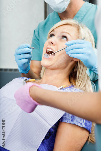 Photo: Dentists Treating A Female Patient At Clinic Dentists Treating A Female Patient At Clinic