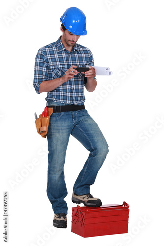 Photo: Laborer using mobile phone Laborer using mobile phone