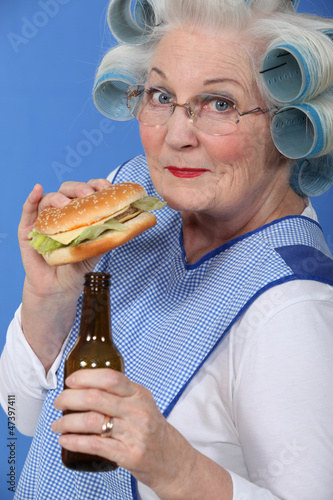 Photo: Old woman in rollers with a burger and a beer Old woman in rollers with a burger and a beer