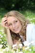 Blond woman laying in a field of daisies