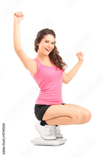 Photo: Happy female on a weight scale gesturing with her hands Happy female on a weight scale gesturing with her hands