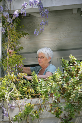 Photo: Old lady looking after the plants on her balcony Old lady looking after the plants on her balcony