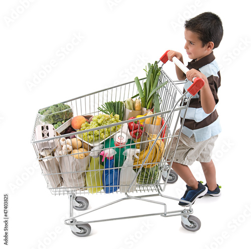Photo: Cute boy walking with shopping trolley isolated on white Cute boy walking with shopping trolley isolated on white