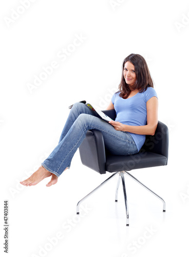 Photo: Young woman sitting in a chair with magazine Young woman sitting in a chair with magazine