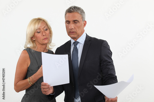 Photo: A couple of businesspeople going through papers. A couple of businesspeople going through papers.
