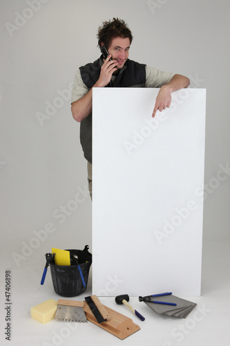 Photo: Tiler using cellphone and pointing to poster Tiler using cellphone and pointing to poster