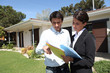Estate-agent stood with client outside house