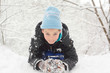 boy lie on snow and sculpt snowball in winter forest