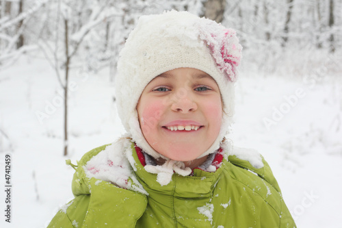 Photo: portrait of little girl in hat with snow in winter forest portrait of little girl in hat with snow in winter forest