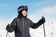 Smiling boy in ski suit against mountains and blue sky