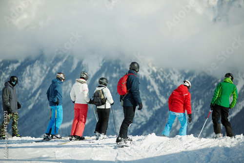 Photo: Group of young skiers stands on edge of snowy hillslope Group of young skiers stands on edge of snowy hillslope