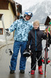Father with snowboard and son with ski on street