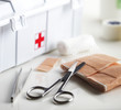 First aid kit with bandage and scissors on white table