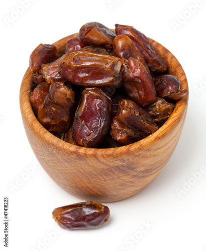 Photo: dried dates in wooden bowl isolated on white dried dates in wooden bowl isolated on white