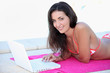 Woman lying beside a pool using a laptop computer