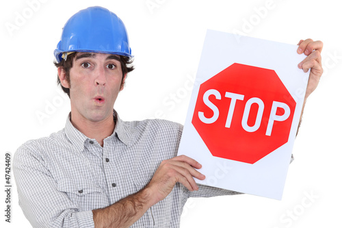 Photo: A road worker holding a stop sign. A road worker holding a stop sign.