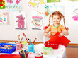 Child with scissors cut  paper  in playroom.