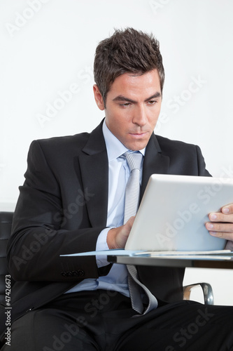 Photo: Young Businessman Using Digital Tablet In Office Young Businessman Using Digital Tablet In Office