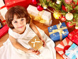 Photo: Child with gift box near Christmas tree. Child with gift box near Christmas tree.