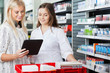 Photo: Woman With Friend Using Digital Tablet At Supermarket Woman With Friend Using Digital Tablet At Supermarket