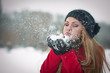 .Young woman with  cap blowing snow, winter fun