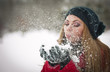 .Young woman with  cap blowing snow, winter fun
