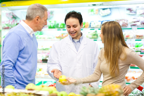Photo: Customers talking with a shop assistant at the supermarket Customers talking with a shop assistant at the supermarket