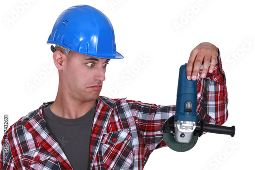 Photo: Uneasy tradesman looking at an angle grinder Uneasy tradesman looking at an angle grinder