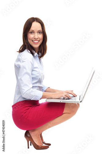 Photo: Businesswoman crouching with laptop Businesswoman crouching with laptop