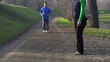 Woman stretching, man jogging in park, crane shot, slow motion