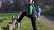 Woman stretching, man jogging in park, slow motion,
