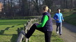 Woman stretching, man jogging in park, crane shot