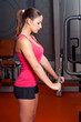 Beautiful young woman exercising arm muscles in the gym