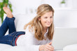 Photo: blonde frau liegt mit laptop auf dem sofa blonde frau liegt mit laptop auf dem sofa