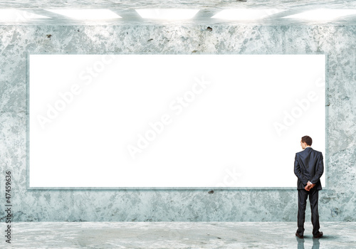 Photo: Business person standing near a blank billboard Business person standing near a blank billboard