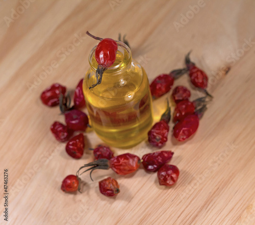Photo: bottle with oil and dried rosehip berries, close-up bottle with oil and dried rosehip berries, close-up