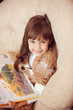 beauty child in shawl reading a book while lying on the couch