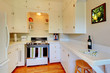 White kitchen with beige walls and cherry hardwood floor.