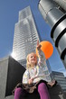 Kleines Mädchen mit Ballon vor Hochhaus